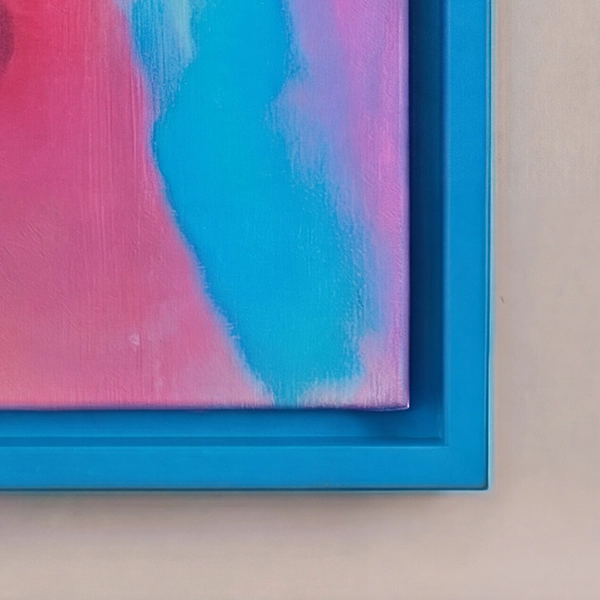 Gros plan d'un cadre américain bleu avec une toile rose et turquoise devant un mur beige clair. Une bordure élégante.