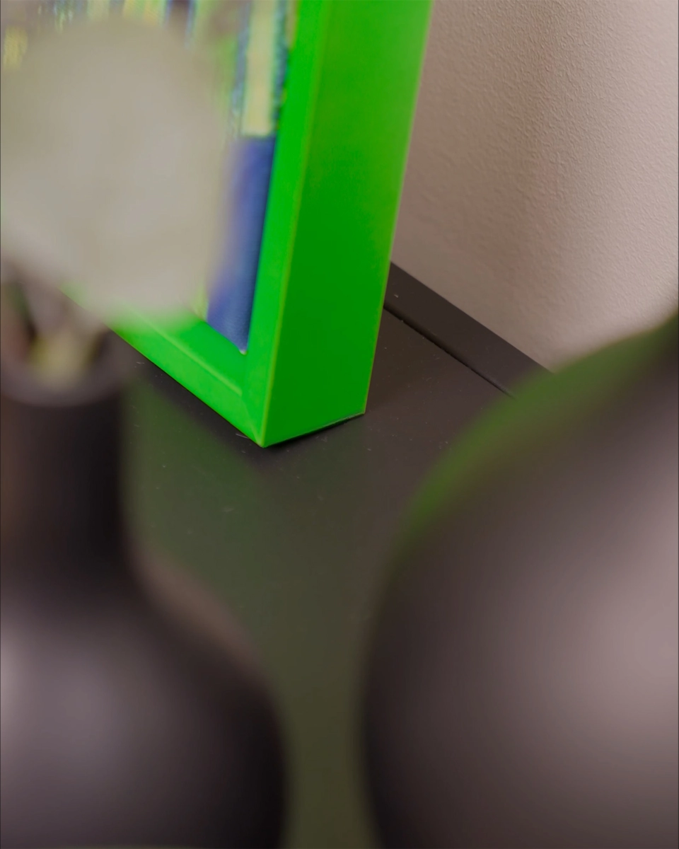 Gros plan sur l’angle du cadre de type caisse américaine Jill en vert néon éclatant pour toiles, dans un intérieur chaleureux.